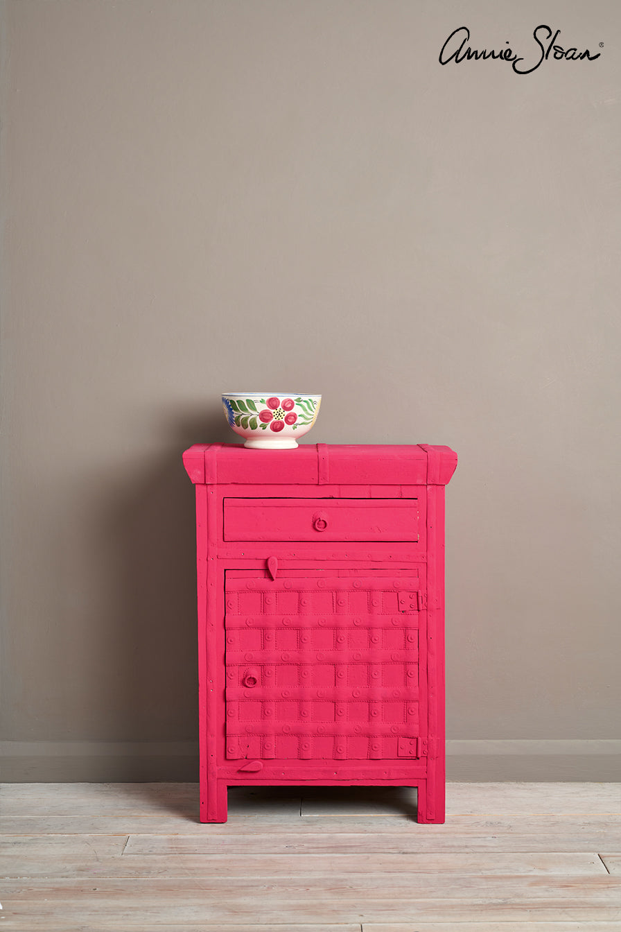 Small side table painted in Annie Sloan Capri Pink Chalk Paint against a wall painted  with French Linen Wall Paint