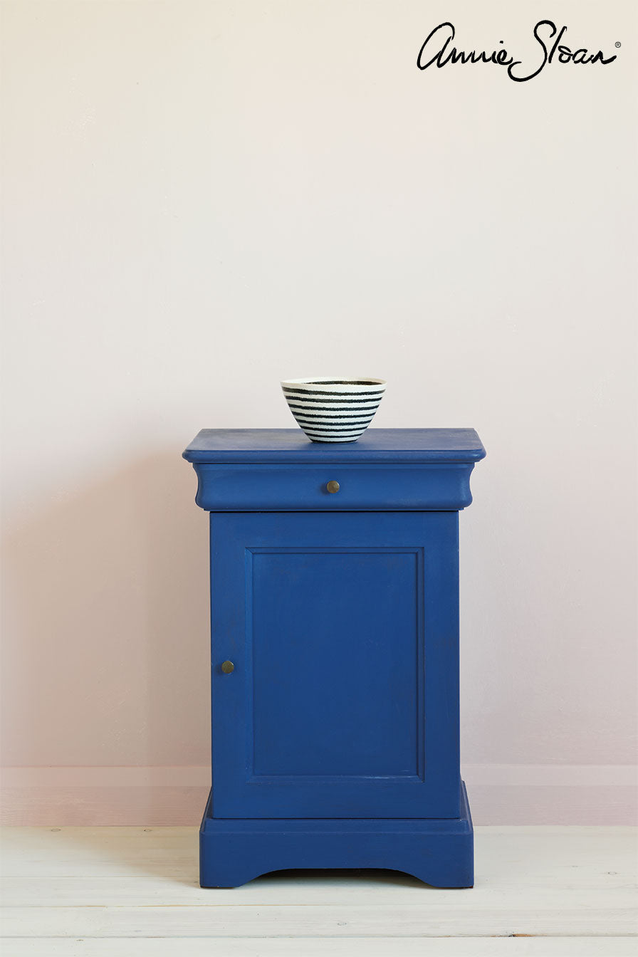 Small cabinet painted in Annie Sloan Napoleonic Blue Chalk Paint against wall painted with Antoinette wall paint by Annie Sloan