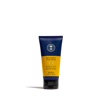 A squeeze tube of Bee Lovely Hand Cream by The Handmade Company, featuring a navy blue and mustard yellow label on a clean white background.