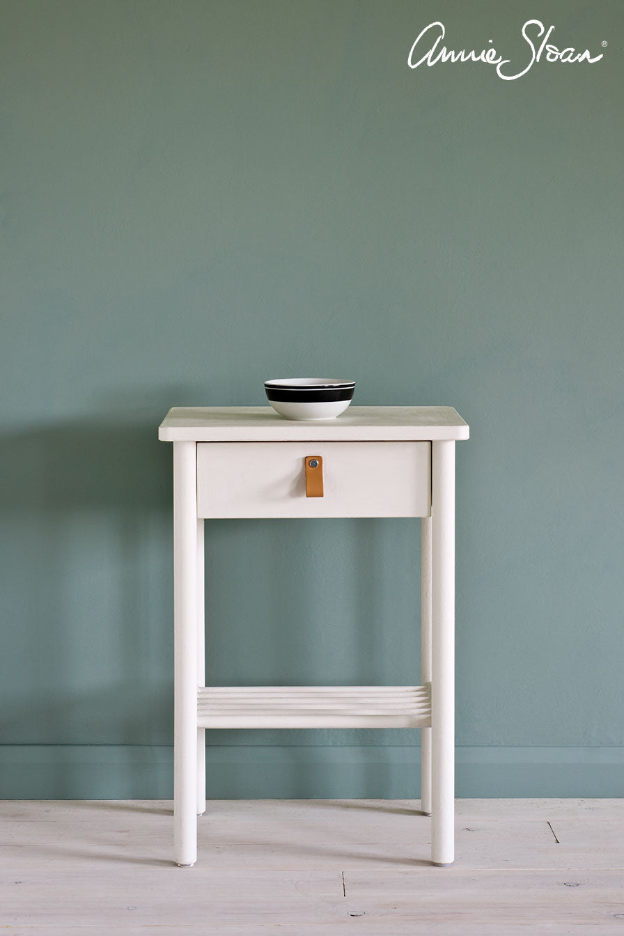 Wooden side table painted with Annie Sloan Old White Chalk Paint against a wall painted with Duck Egg Blue Wall Paint