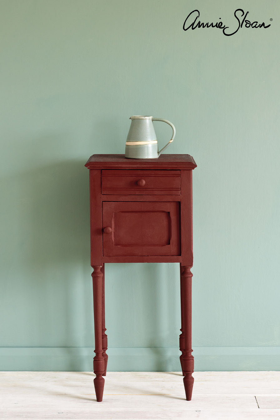Vintage side table painted in Annie Sloan Primer Red Chalk Paint against a wall painted with Duck Egg Blue Wall Paint